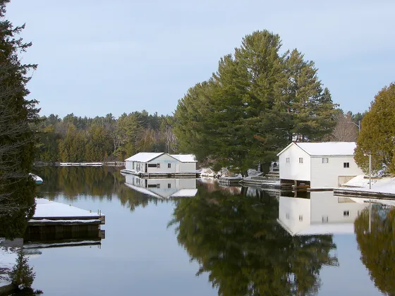 Boathouses and docks reflected in the water at Baysville, Ontario, in winter.