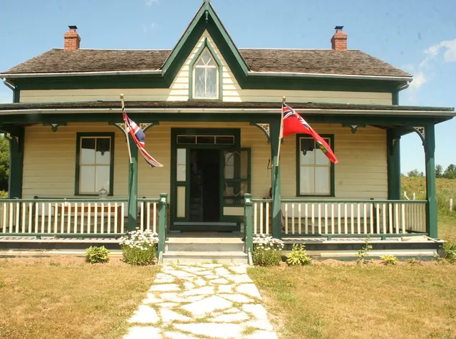 A traditional farmhouse with a covered front porch and lawn at Grey Roots, Owen Sound, Ontario.